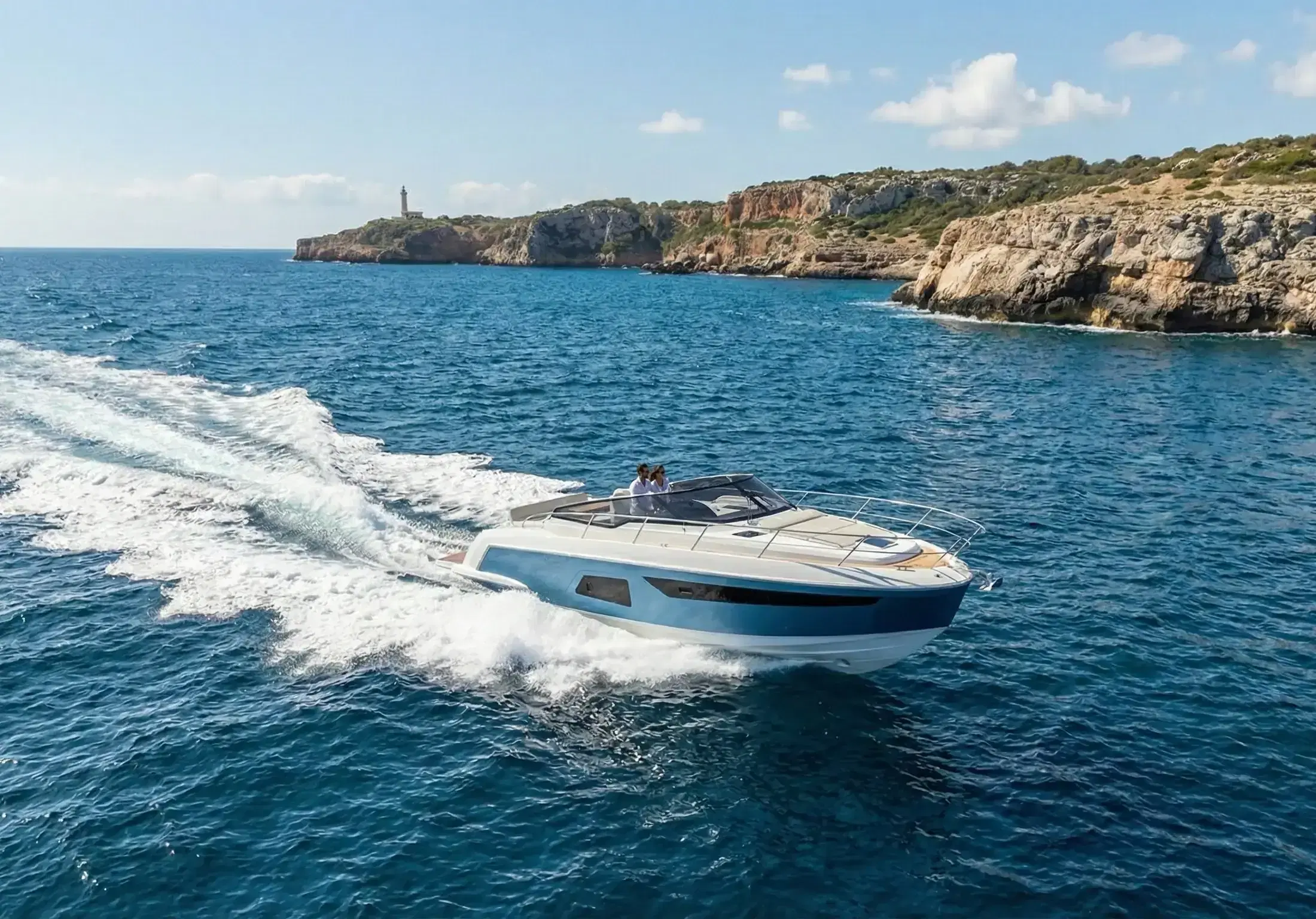Motorboot mit zwei Personen auf dem Meer vor einer Felsküste mit Leuchtturm